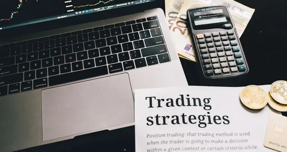 Close-up image of a trading setup with a laptop, calculator, and financial documents, ideal for finance and stock market themes.