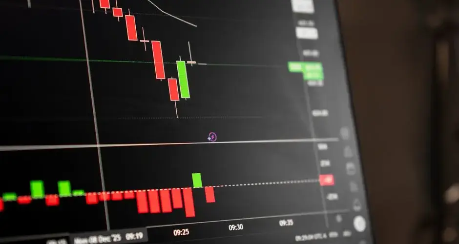 A close-up of a digital screen showing stock market candlestick chart data.
