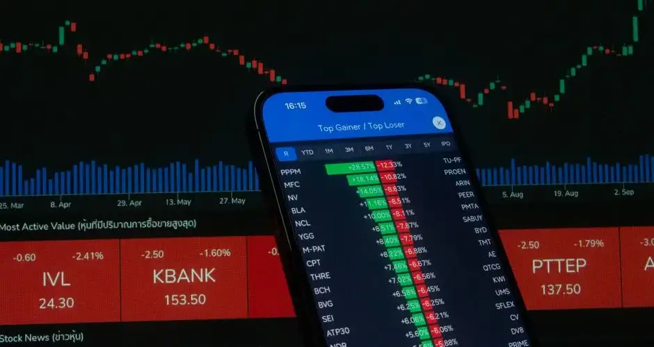 Smartphone with stock market data in front of financial chart.