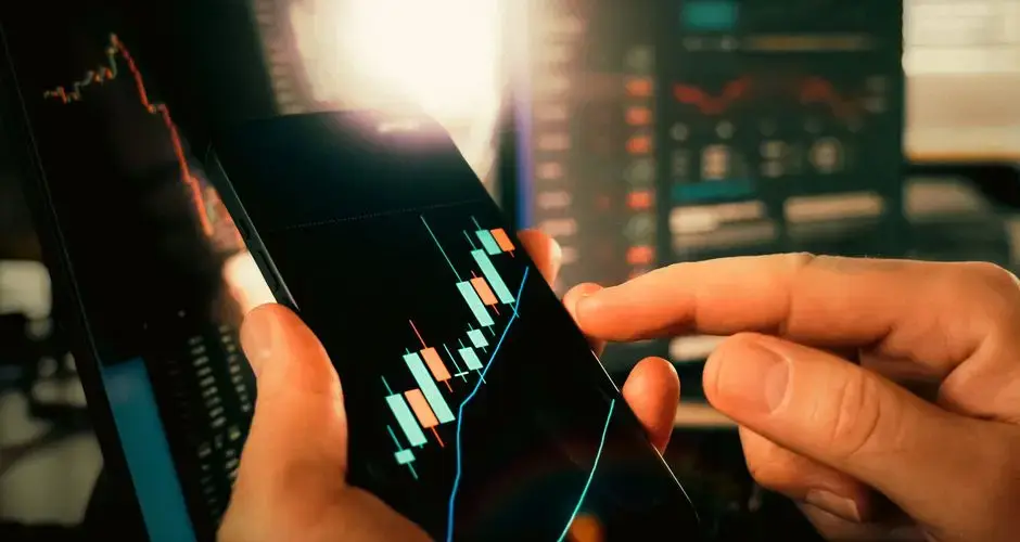 Hands interacting with financial charts on a smartphone, showcasing stock market trends.