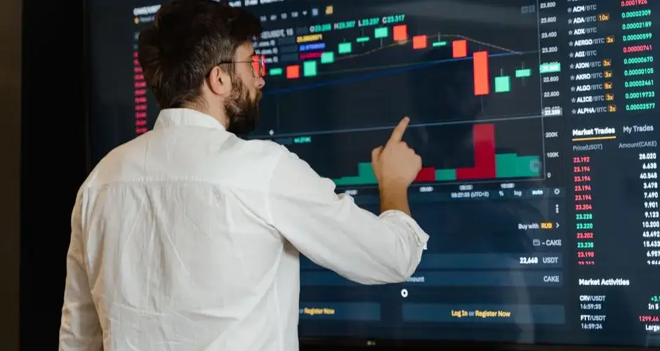A man analyzes cryptocurrency graphs on a touchscreen monitor in a modern office setting.