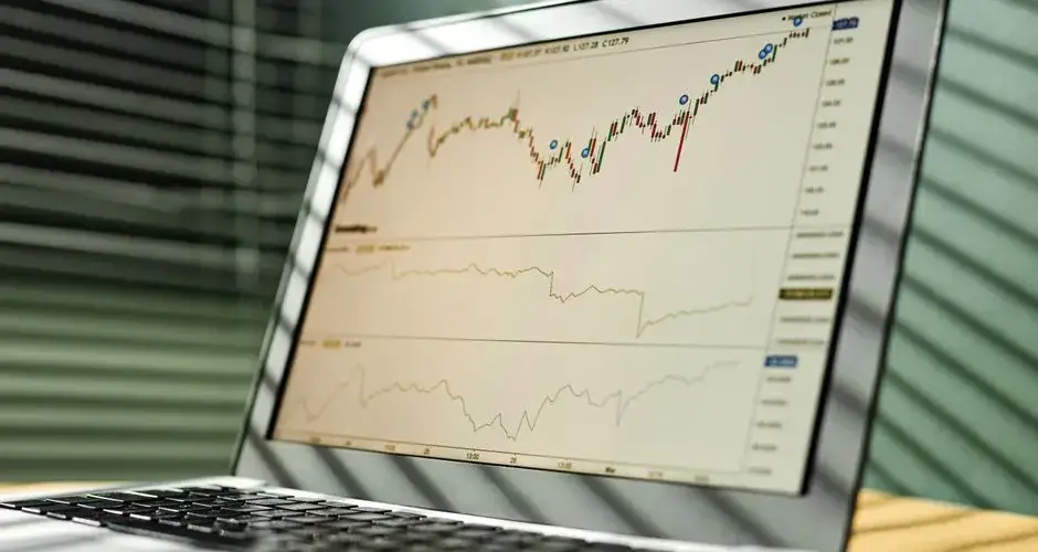 Close-up of a laptop displaying stock market data and graphs in an office setting.