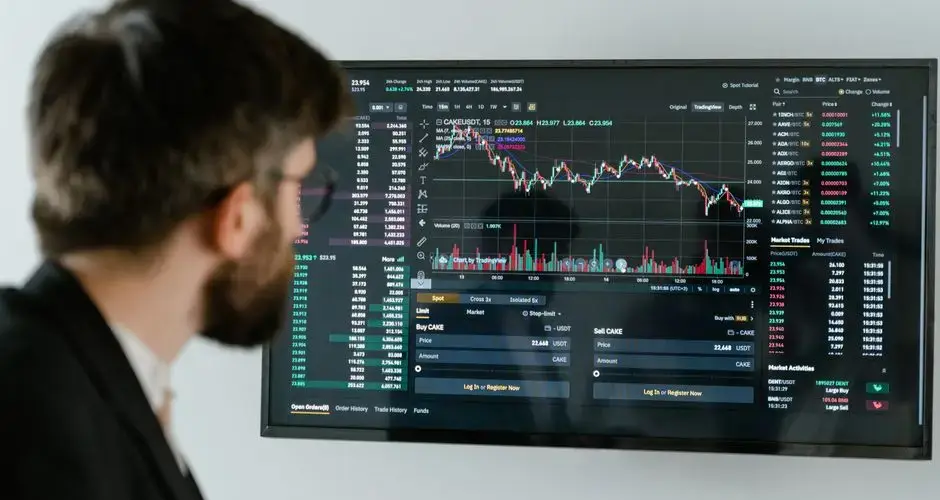 A businessman in a suit looks at a screen displaying stock market charts and data analysis.
