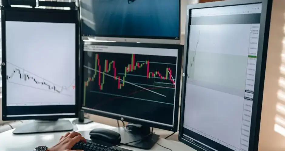 A multi-monitor stock trading setup showcasing charts and data analysis in a home office setting.