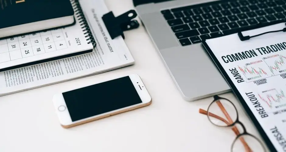 A well-organized office desk setup with finance documents, digital devices, and glasses.