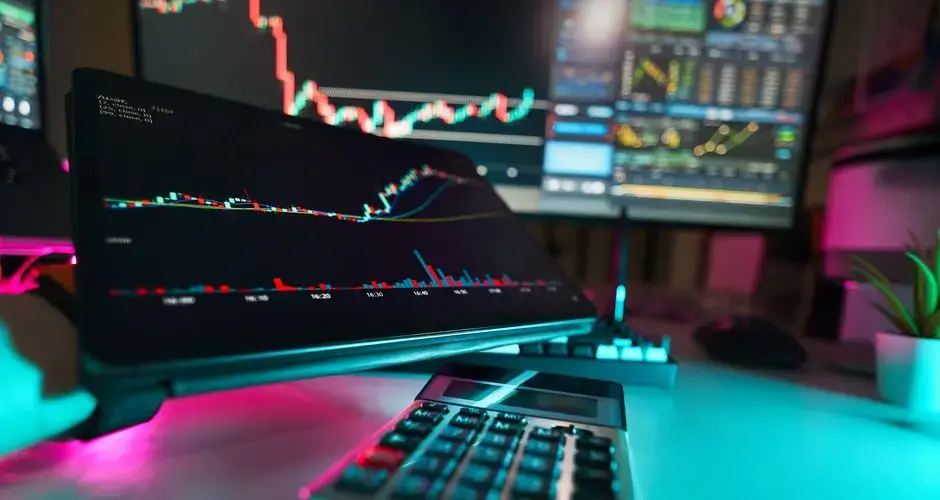 A vibrant office setup with digital tablets displaying financial analysis and stock charts, complemented by a calculator.