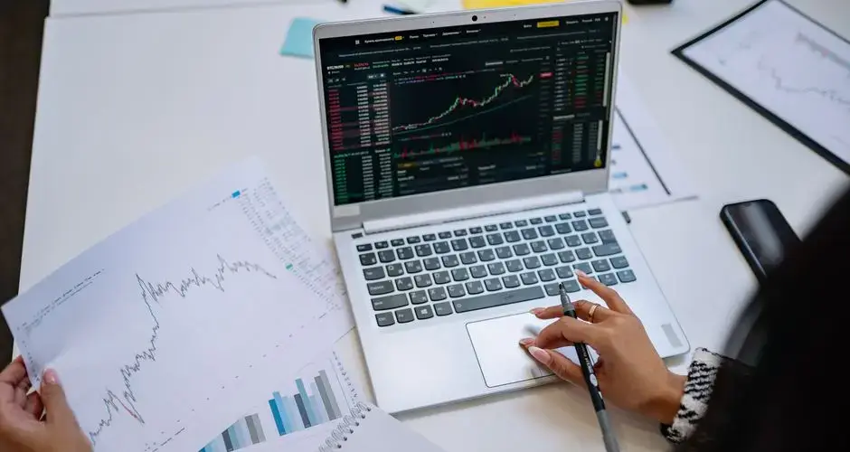 A detailed look at business analysis with a laptop displaying graphs and financial charts on a table.