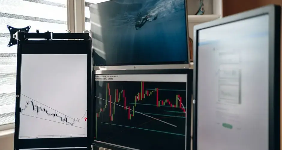 A home office setup featuring multiple monitors displaying trading charts and data analysis.