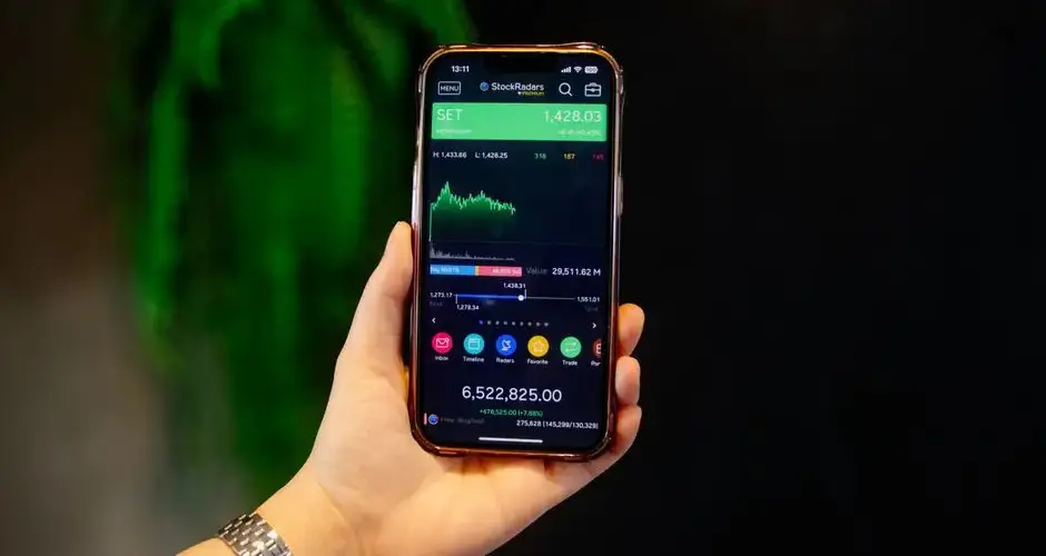 Close-up of a hand holding a smartphone displaying a stock trading app with real-time data.