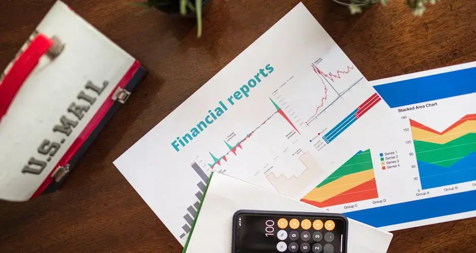 Overhead view of financial reports, charts, and a calculator on a desk.
