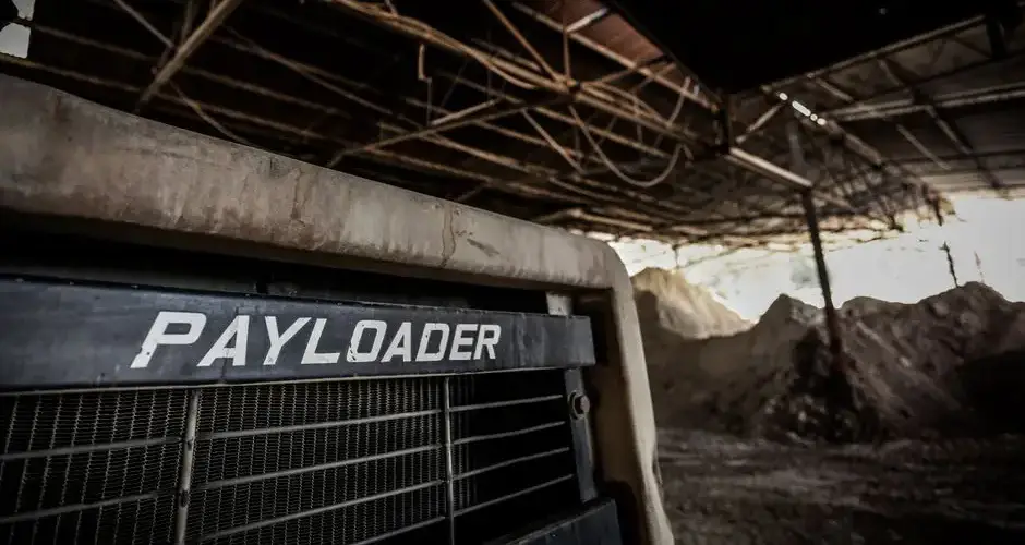 Close-up of a payloader in a dusty warehouse setting, showcasing heavy industrial machinery.