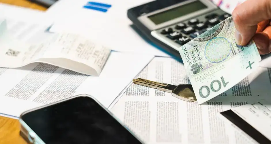 Close-up of financial documents, calculator, and Polish Zloty currency on a desk.