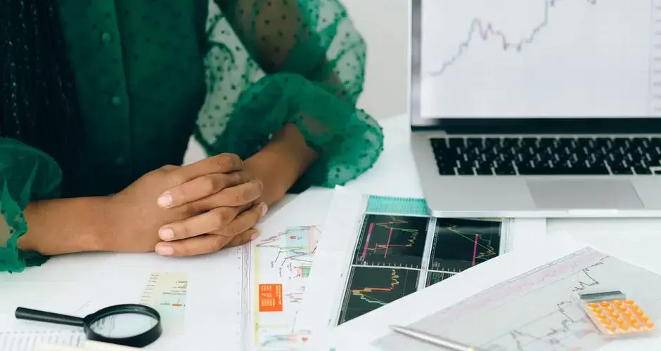 A person analyzes financial charts and graphs at a desk, indicating business trading activity.