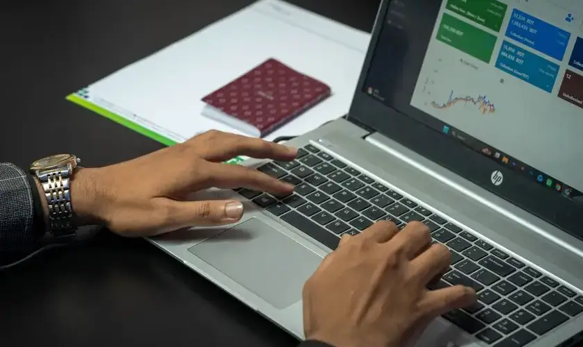 Close-up of hands on a laptop keyboard with a business dashboard on screen, ideal for finance or tech themes.