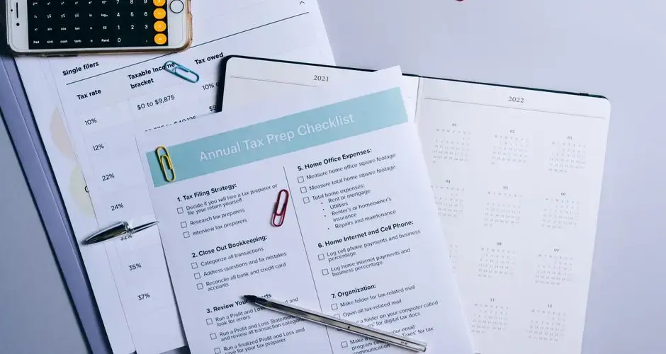 Flat lay of a tax preparation checklist, calculator, and financial documents on a desk.