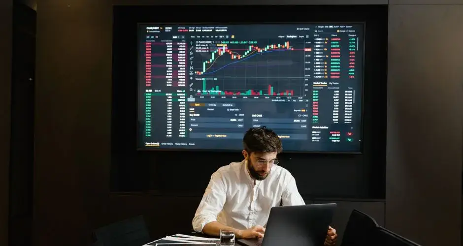 Businessman using laptop in office analyzing stock market charts. Professional finance and investment concept.