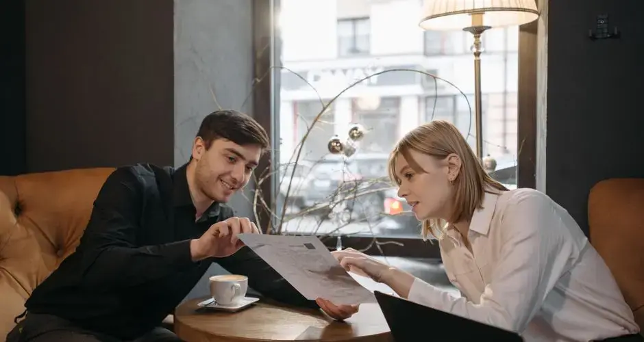 Two colleagues discuss a document while enjoying coffee in a modern café.
