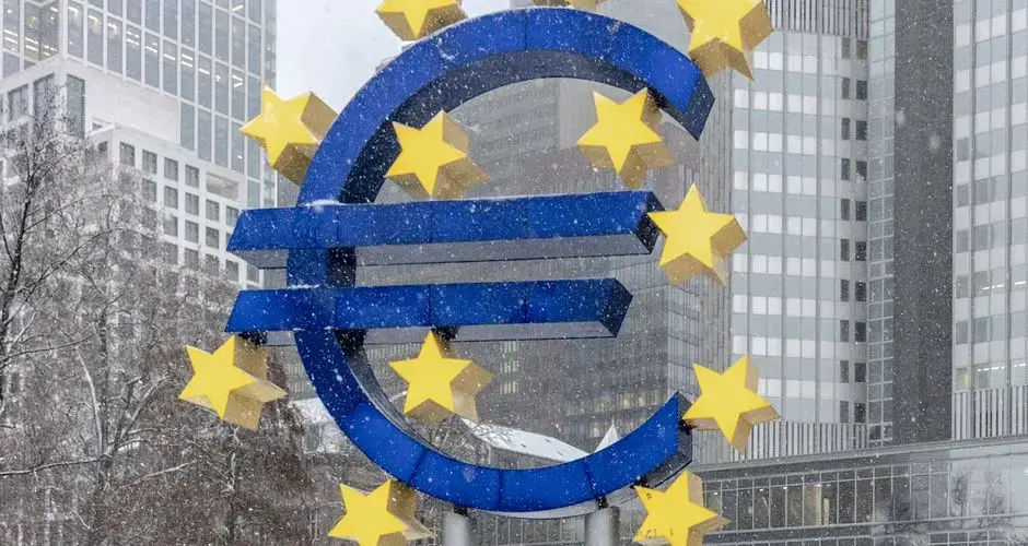 The iconic Euro symbol stands prominently amidst snowy Frankfurt skyscrapers.