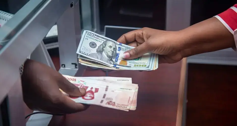 Hands exchanging US and local currency at a bank counter, signifying international finance.