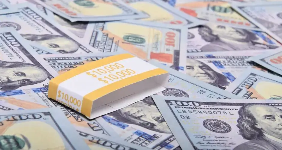 A stack of $100 bills arranged on a surface with US dollar notes. Ideal for finance themes.